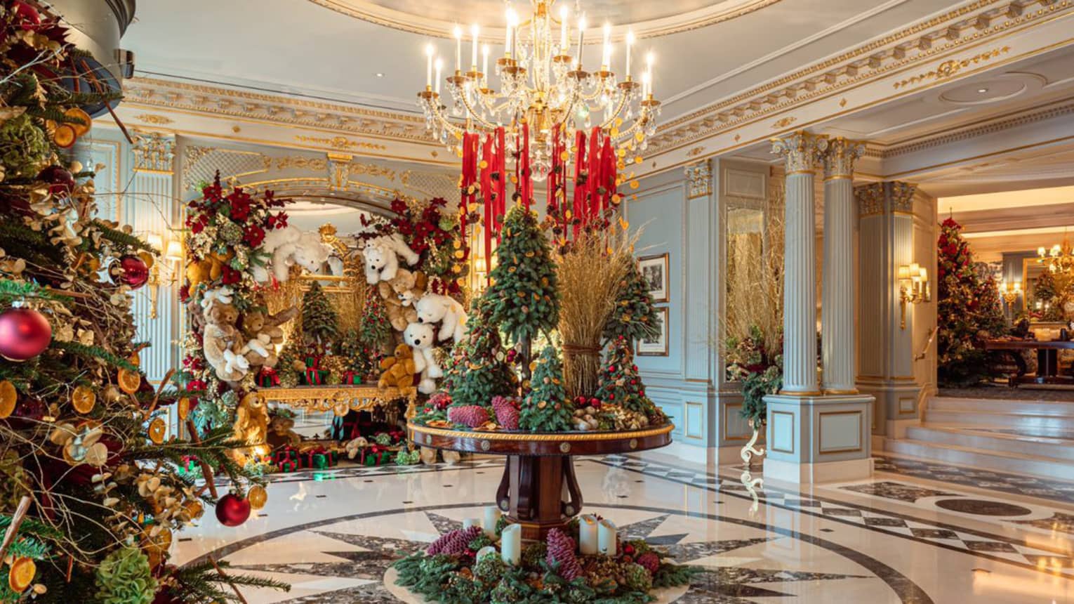 Elegant hotel lobby circular table topped with Christmas tree d�cor under a crystal chandelier