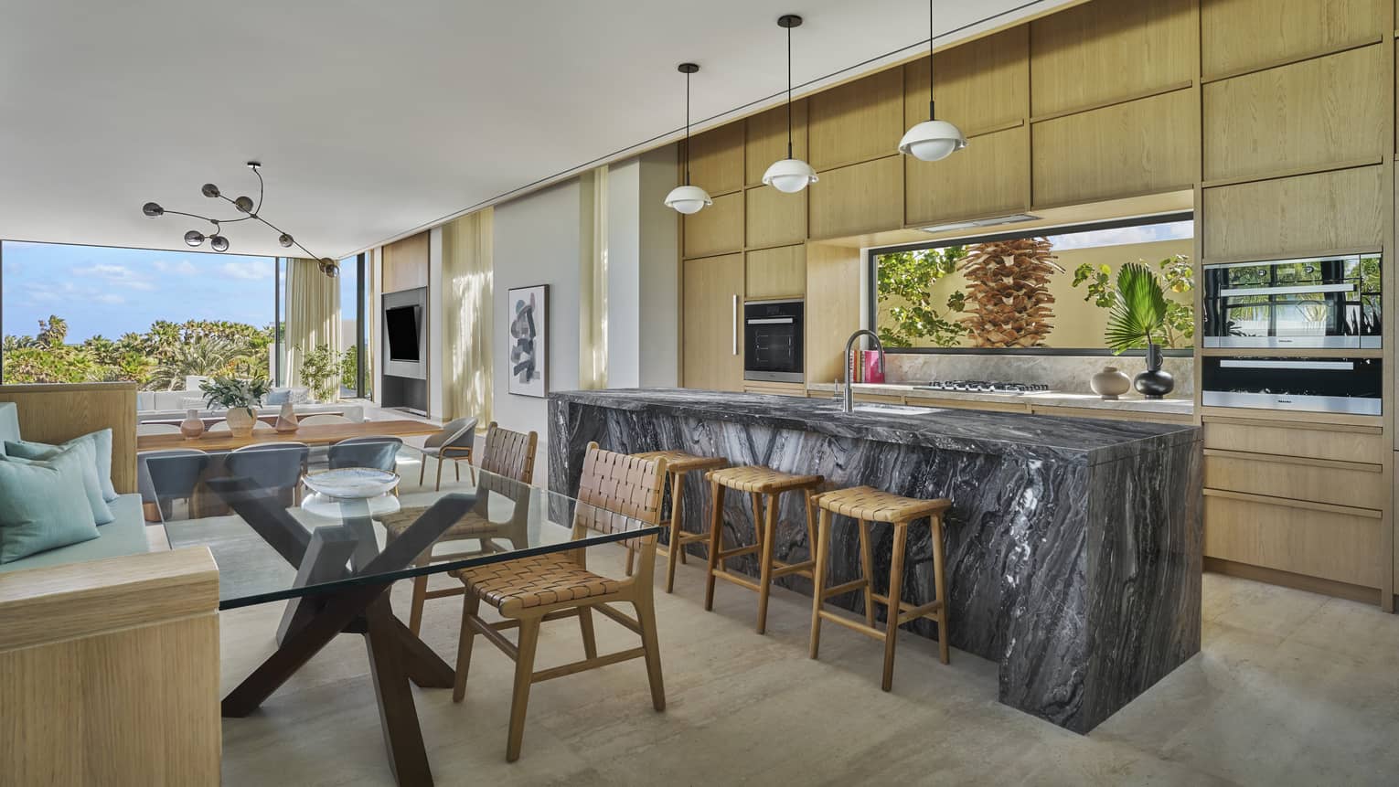 Modern kitchen with dark stone island and glass dining table in a private villa at Four Seasons Resort and Residences Los Cabos