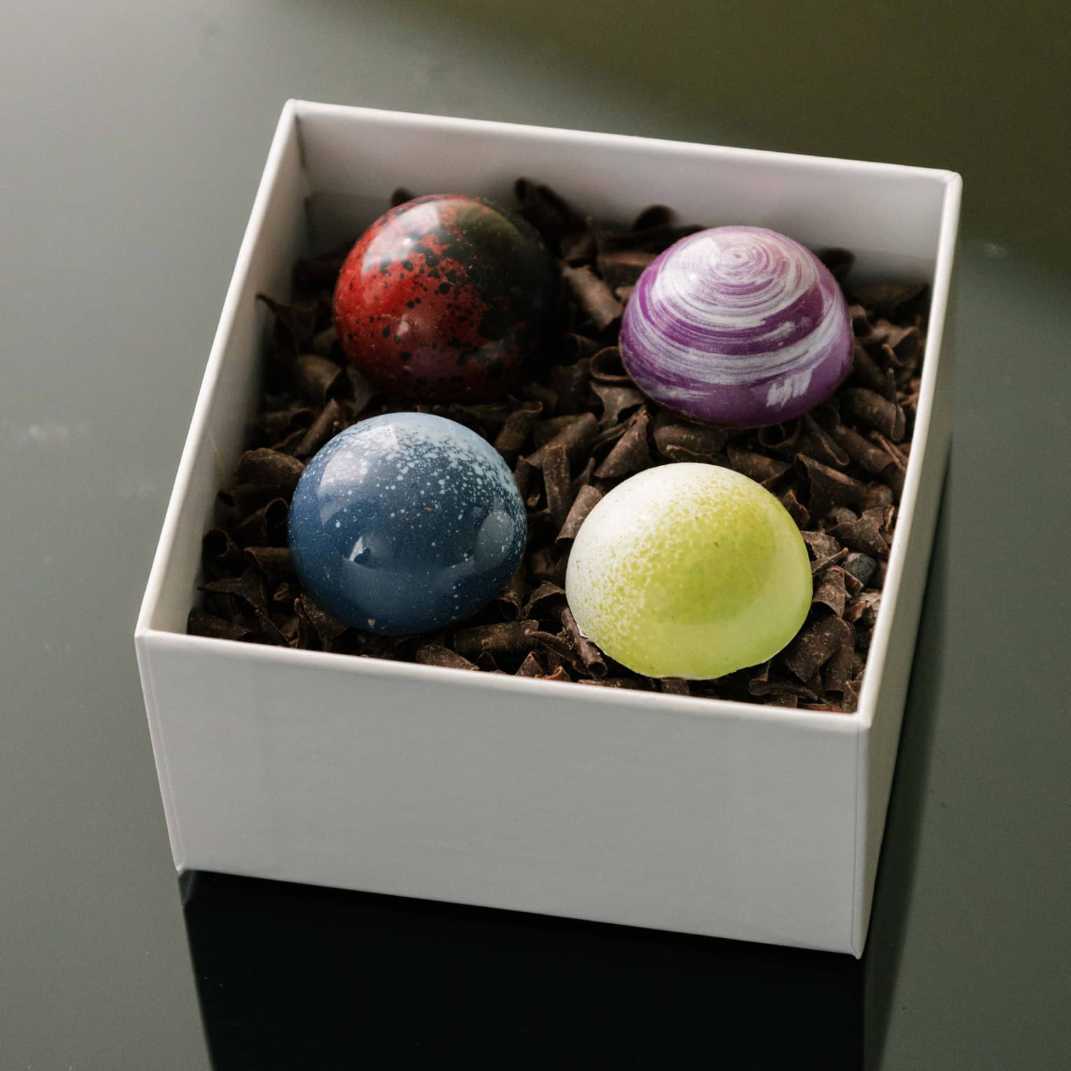 Box of chocolates with blue, yellow, purple and red coloured chocolates.