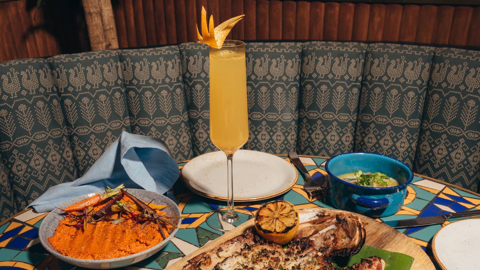 Plates of food on a table with a yellow and blue design, and a plant in the background.