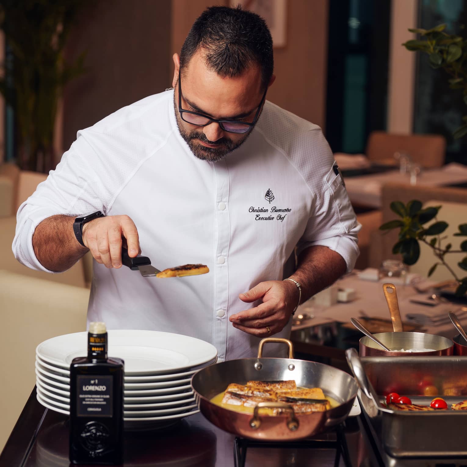 Chef carefully places a filet of fish onto a white plate at a buffet live station