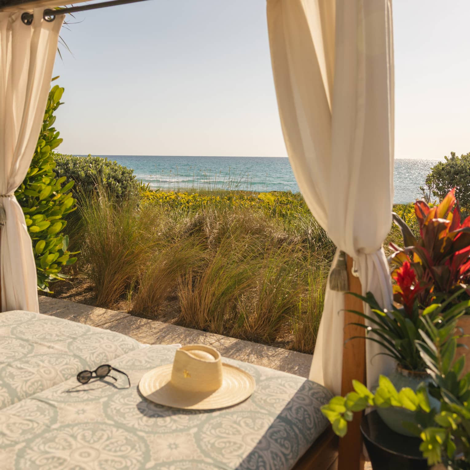 Beachside cabana overlooking the ocean with a hat lying on the cushion