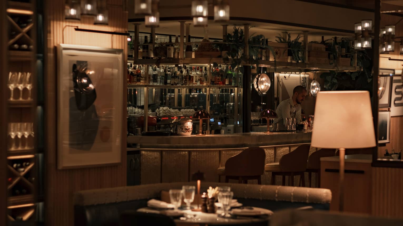 A cozy indoor dining space with dark wood and earth-toned decor and warm light from table and ceiling fixtures