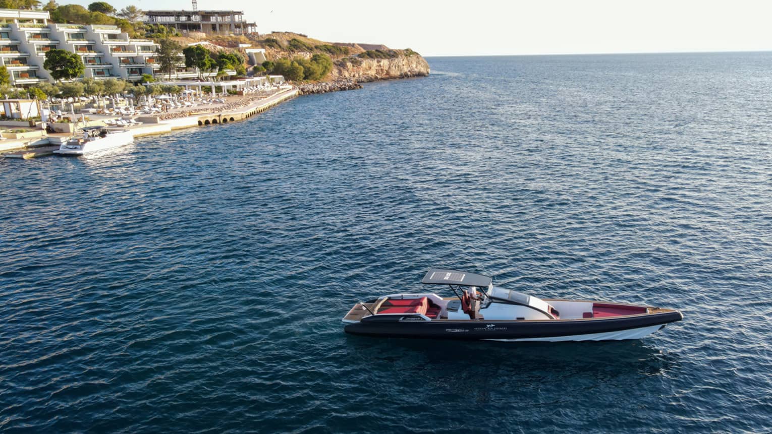 Small Greek-style yacht heading out toward open water from Astir Palace Hotel dock.