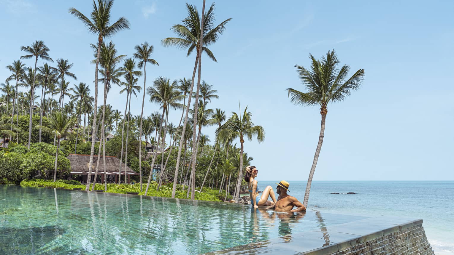 Couples relaxes in beachfront infinity-edge pool