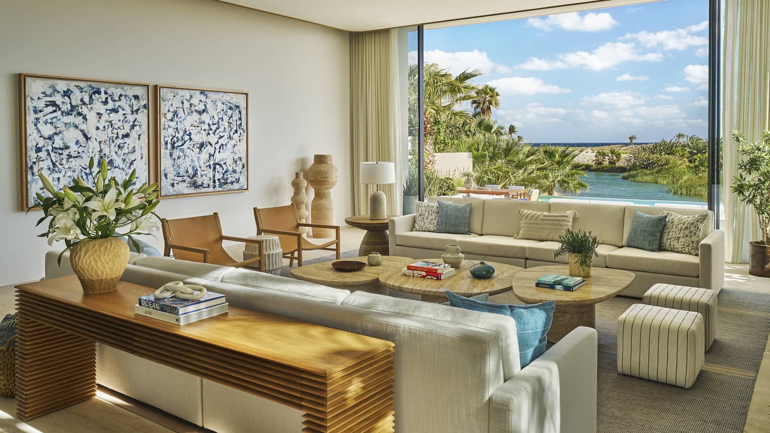 Light-filled living room with two sofas facing a cluster of three coffee tables, in a private villa at Four Seasons Resort and Residences Los Cabos