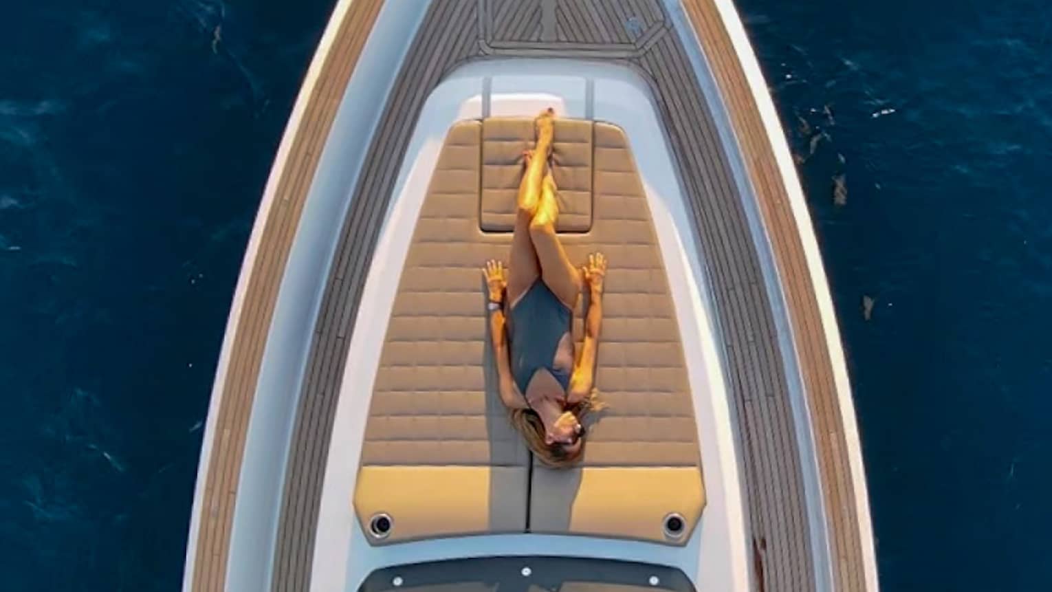View from above of woman sunbathing on front deck of yacht.