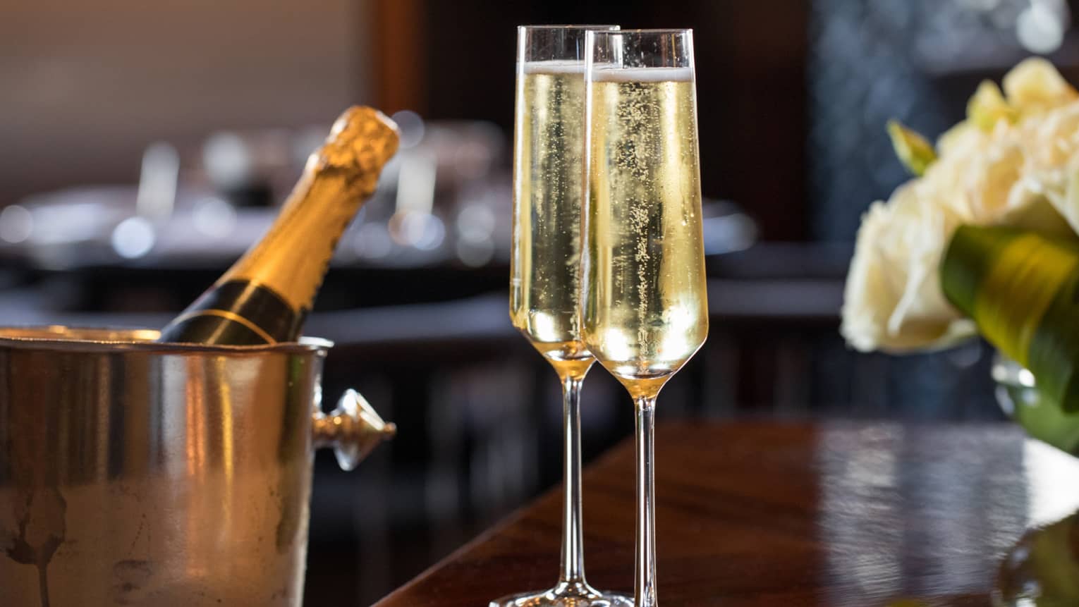 Close-up of two glasses of bubbly Champagne, bottle in ice bucket