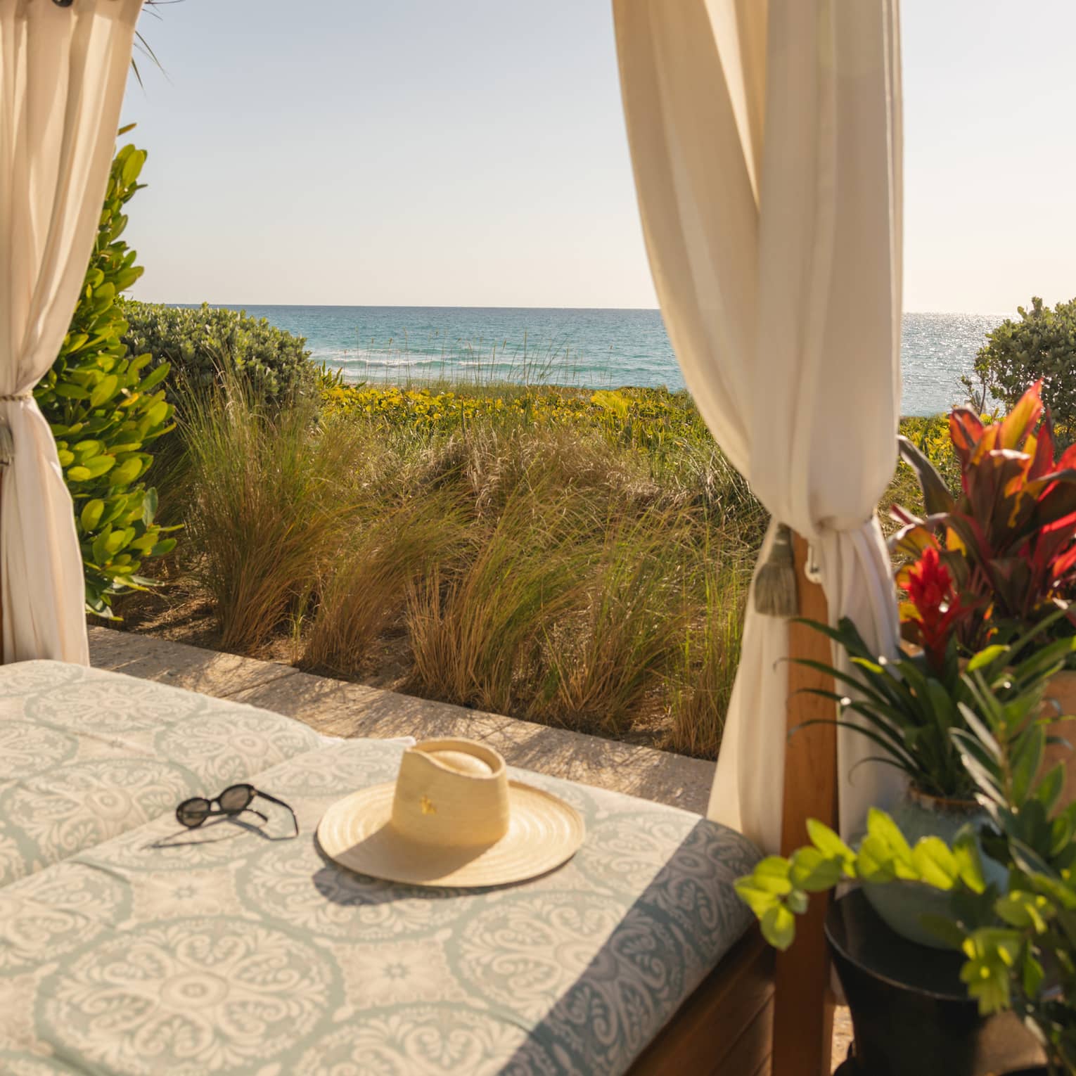 Beachside cabana overlooking the ocean with a hat lying on the cushion