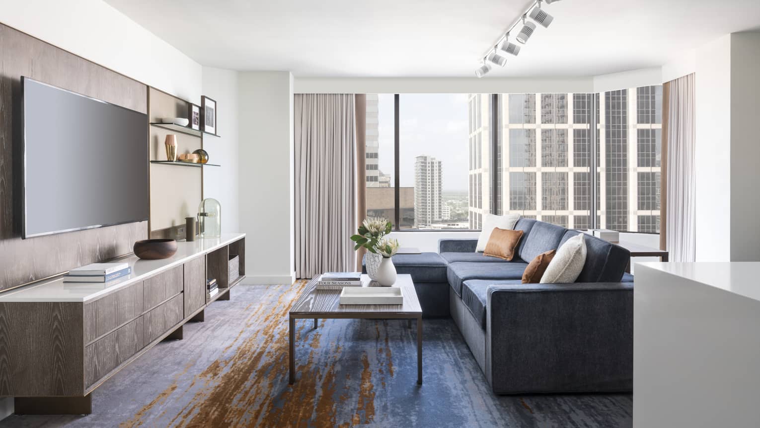 Two-bedroom Residential Suite living area with navy sectional sofa, floor-to-ceiling windows, city views