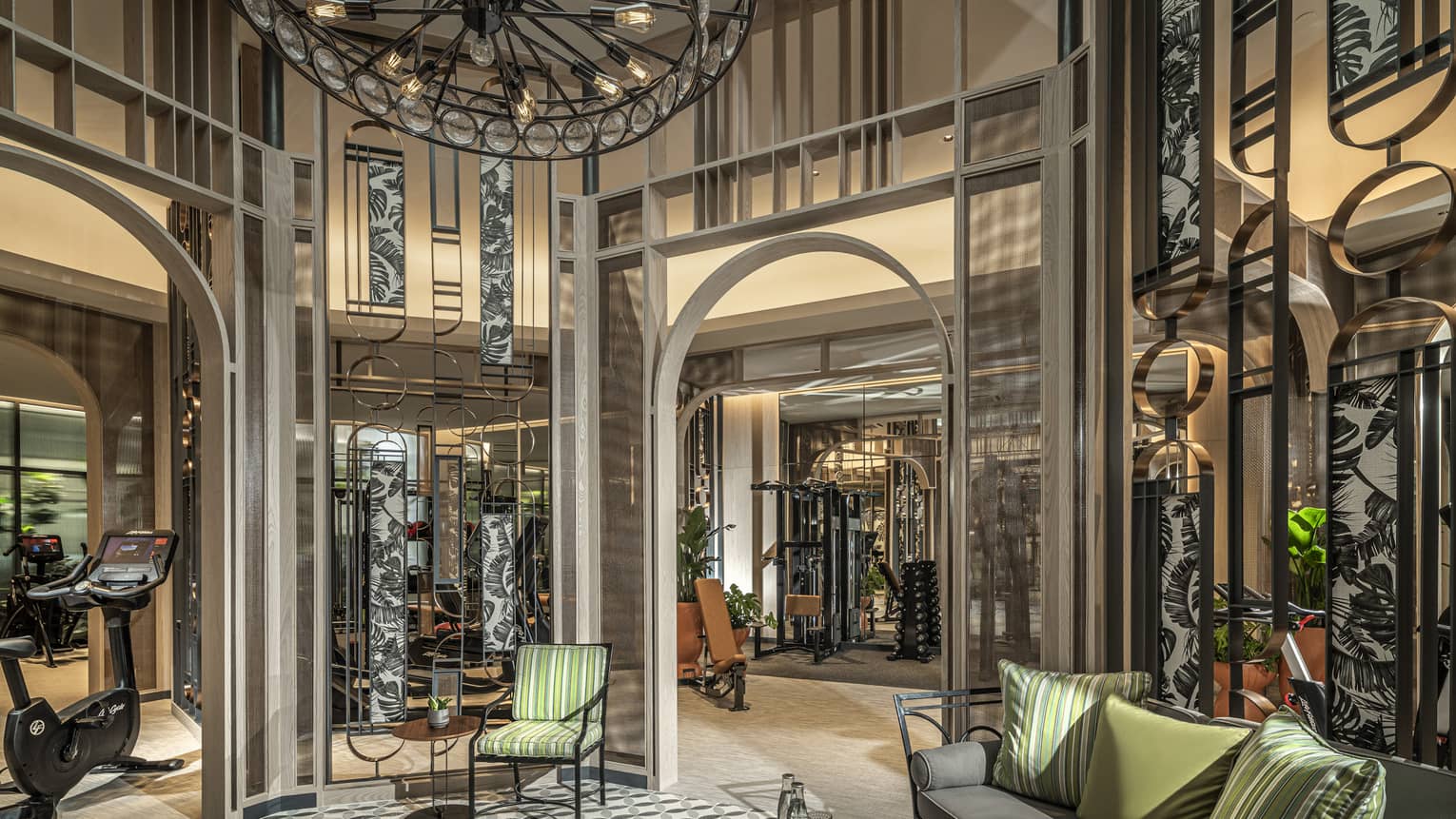 Fitness Centre lobby with high ceilings, round wrought-iron chandelier, sofa with green accent pillows