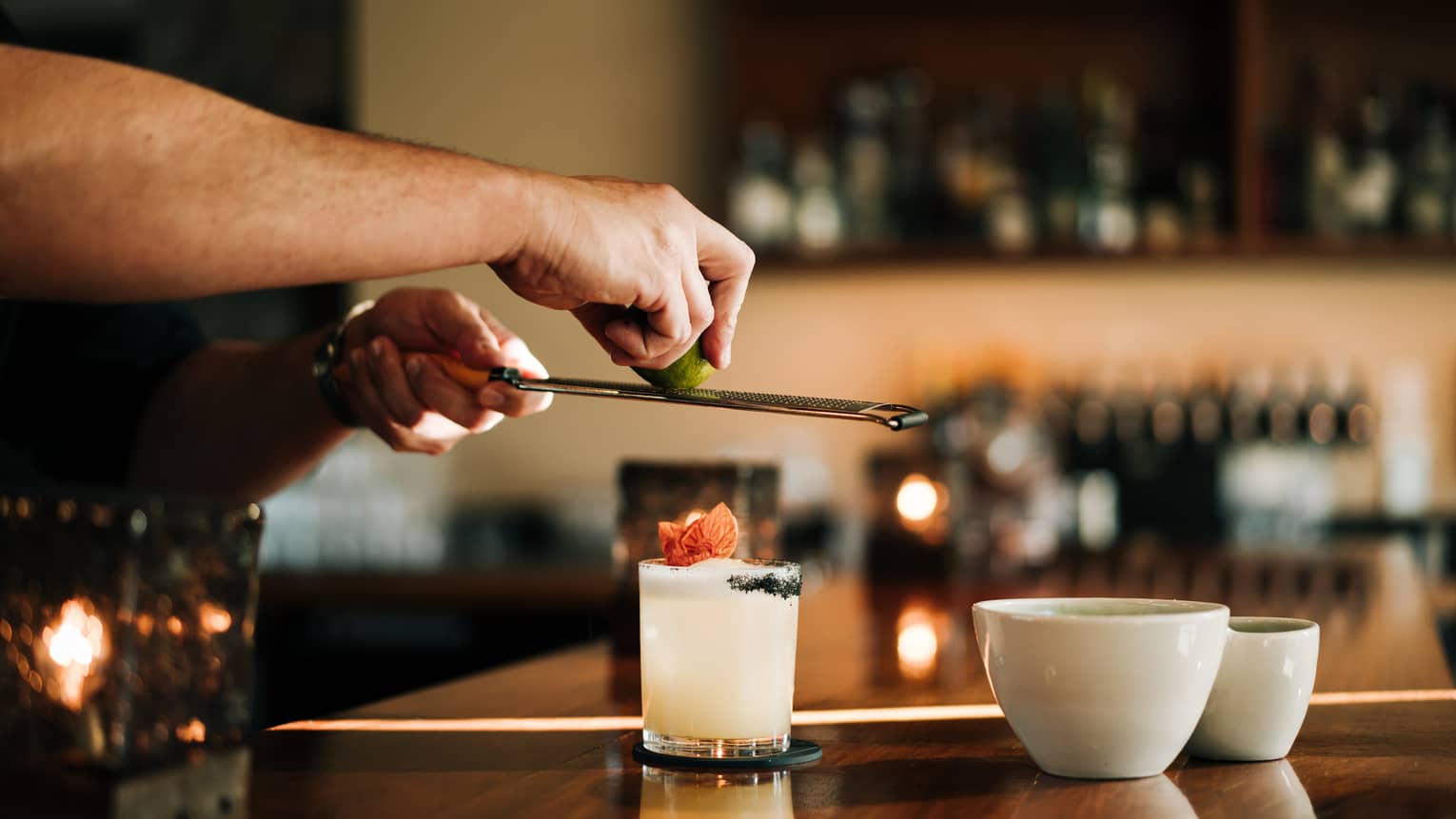 A person standing at a bar and making a drink in a glass