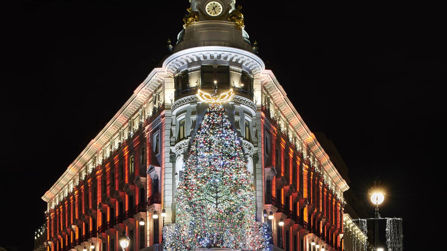 Four Seasons Hotel Madrid at night with illuminated Christmas tree at front entry