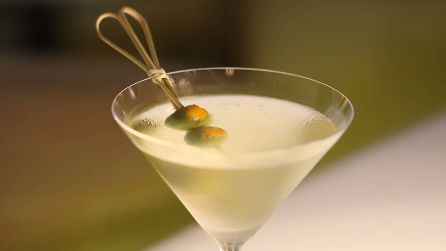 A mango drink in a glass with olives