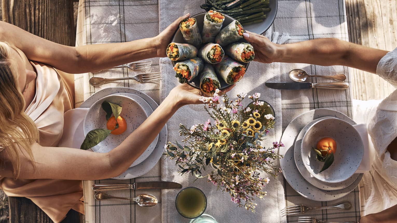 Guests sitting around a table and passing bowls of food.