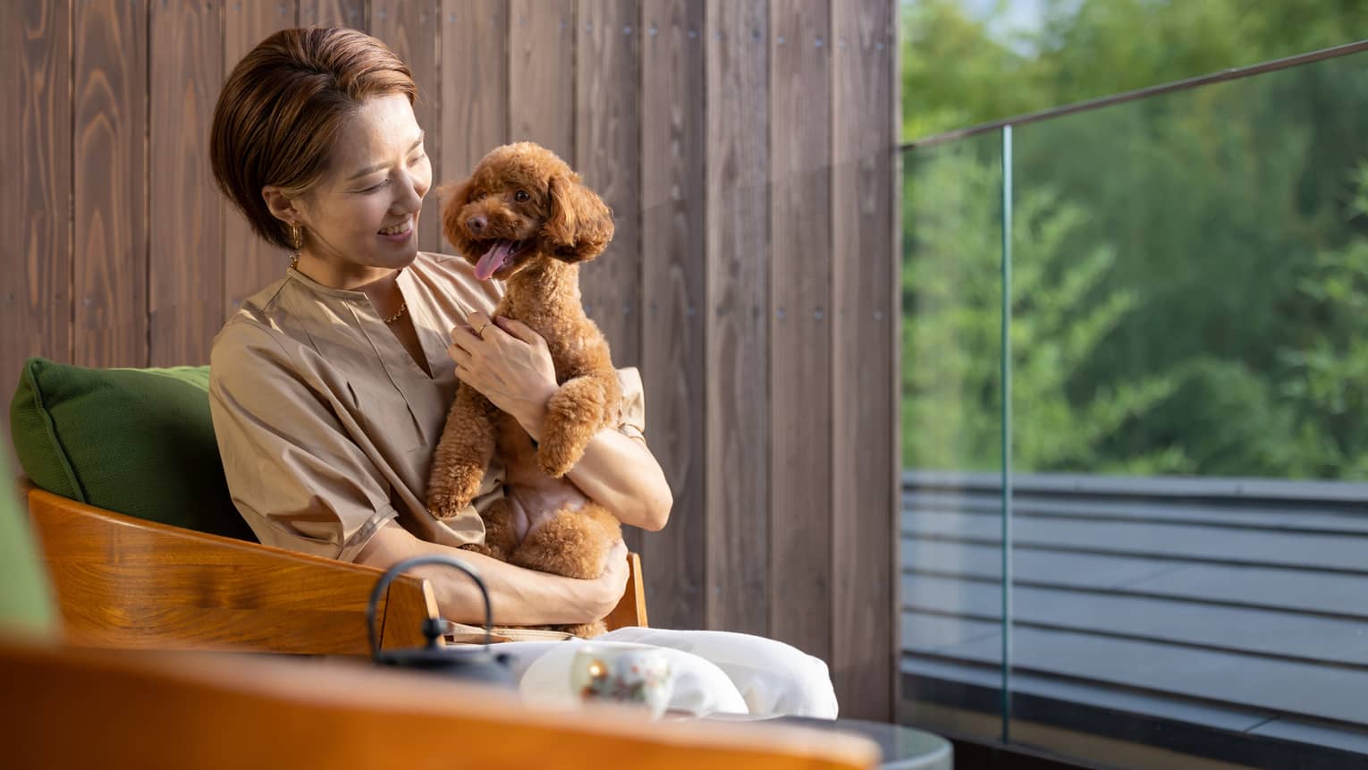 Female guest cuddles with her toy poodle on a balcony