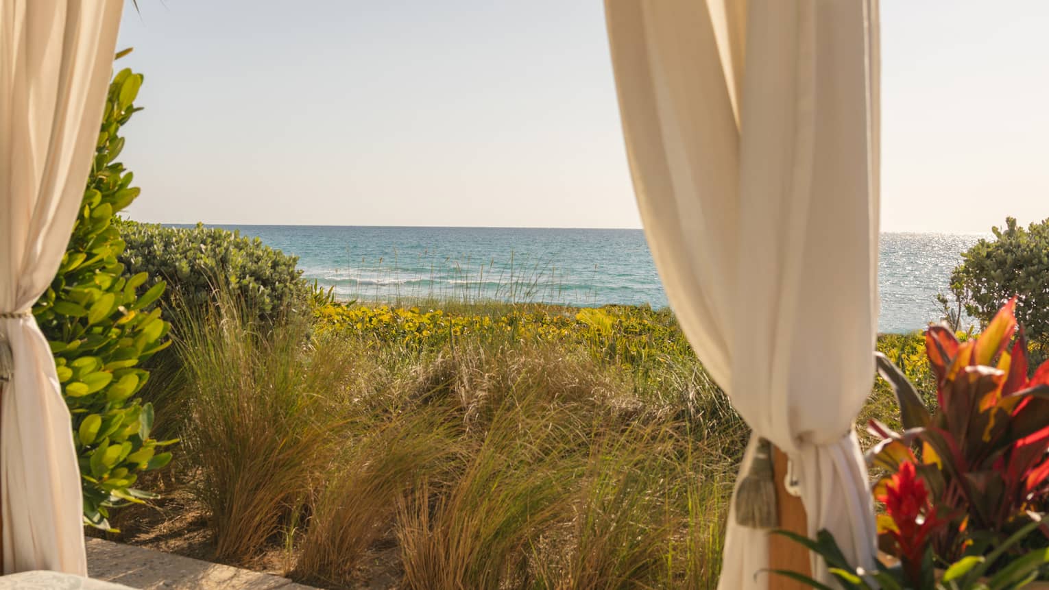 Beachside cabana overlooking the ocean with a hat lying on the cushion