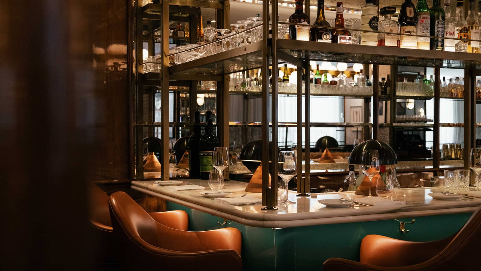 The corner of a bar with tiered shelves and brown leather barstools