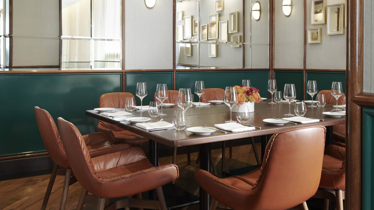 Private dining room with mirrored walls, dark green accents and a rectangular table with brown-leather seats