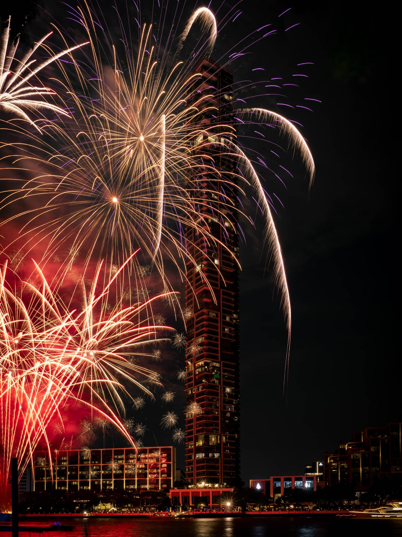Colourful fireworks are set off at night by the river