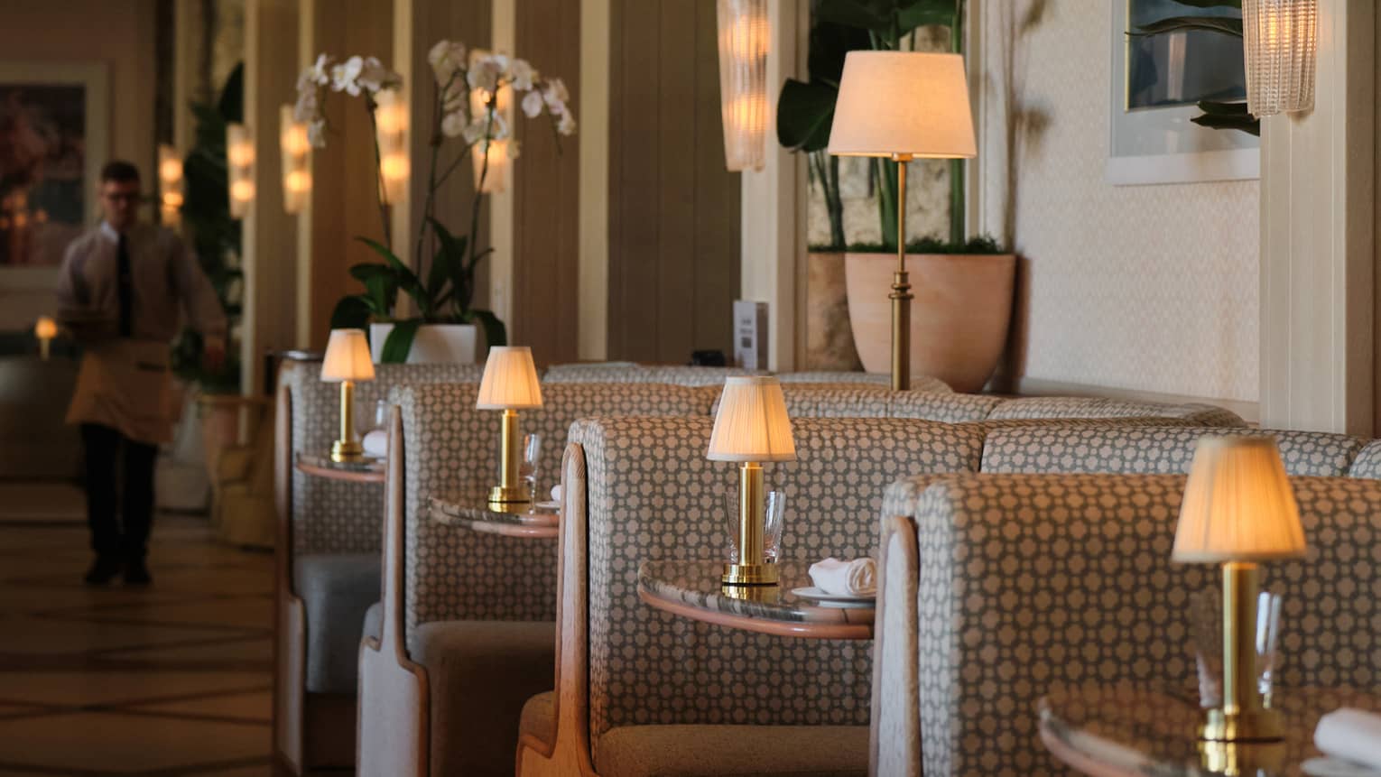 A line of booths in a restaurant, each topped with a lamp