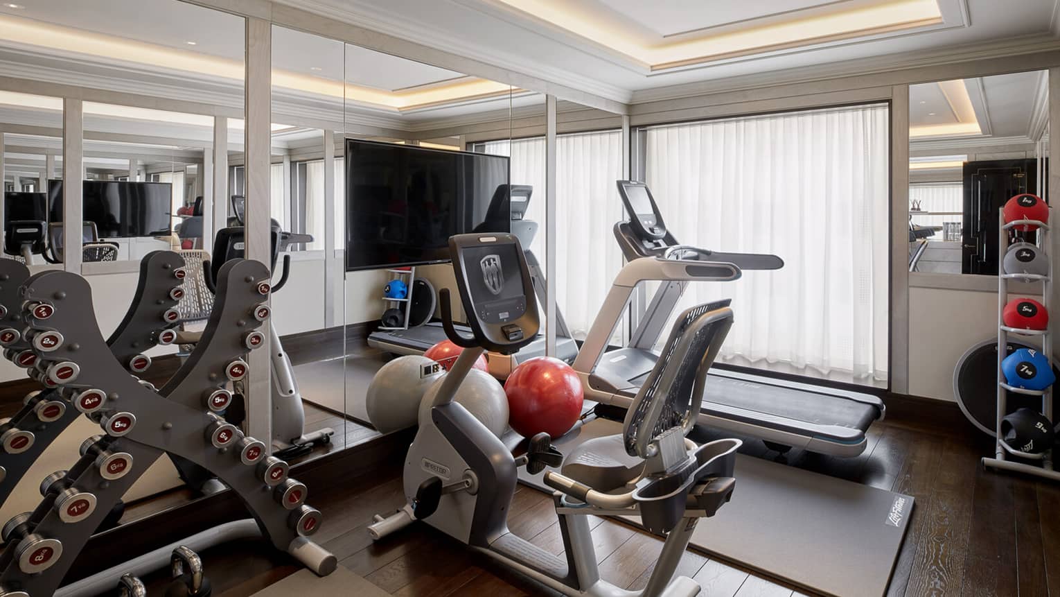 Private gym in penthouse suite at Four Seasons Hotel London at Ten Trinity Square, with treadmill, bike, weights and TV