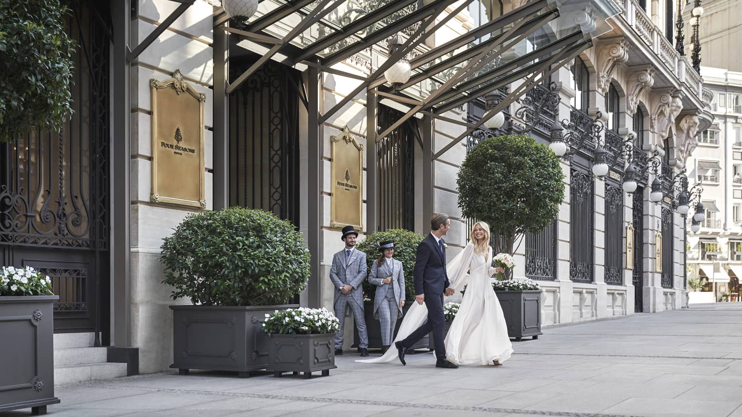 A wedding couple walking out the front door of the hotel.