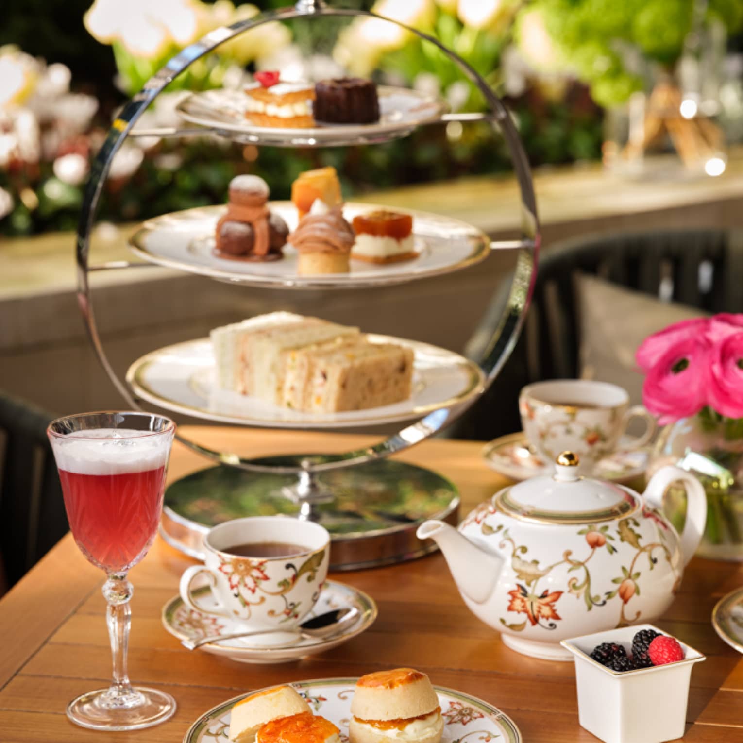 Afternoon tea service with floral teapot, cups, desserts on tiered tray