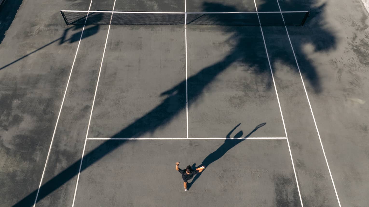 Aerial view of tennis player serving the ball on a clay court
