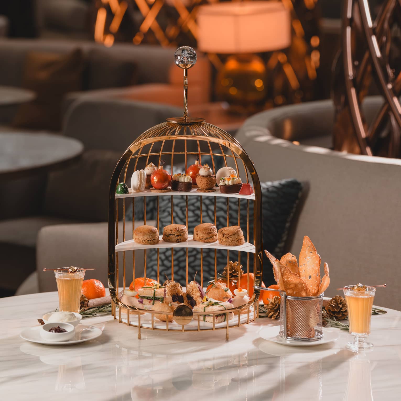 White marble table set for afternoon tea with a three-tiered pastry tray and two cups of tea