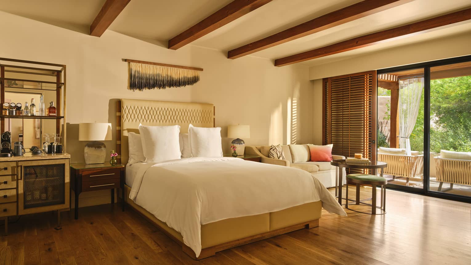 Luxury bedroom with king bed, wet bar area, sofa and coffee table, and walk-out terrace
