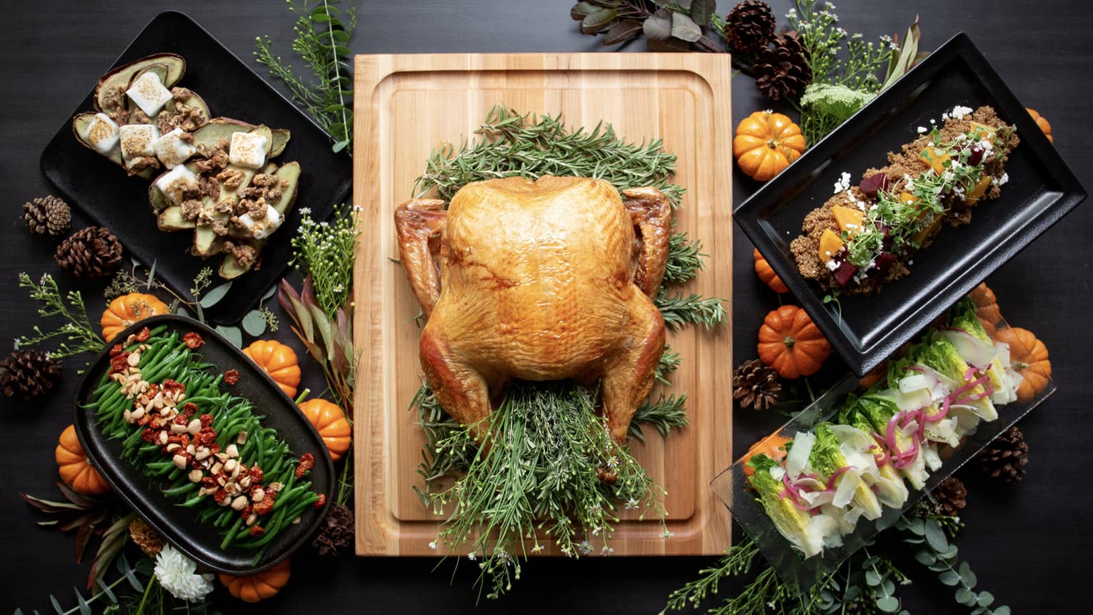 A turkey on a wooden board with other Thanksgiving foods around it.