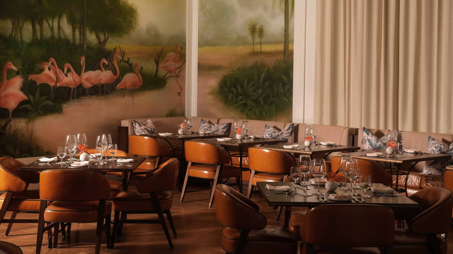 Dining room with brown leather chairs, rectangular tables and a large mural featuring flamingos