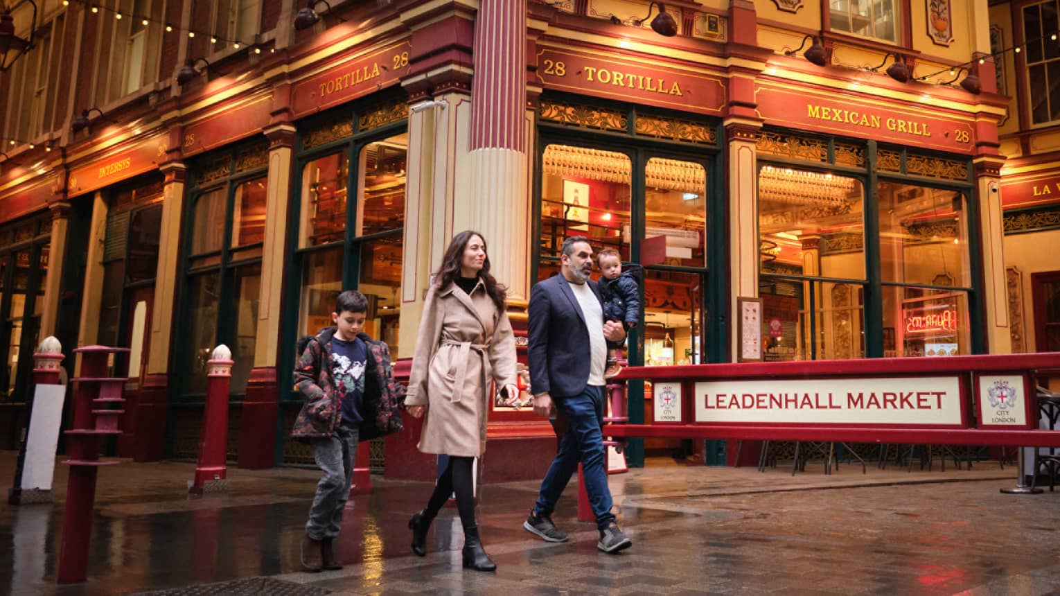 A family walks through London city street at night