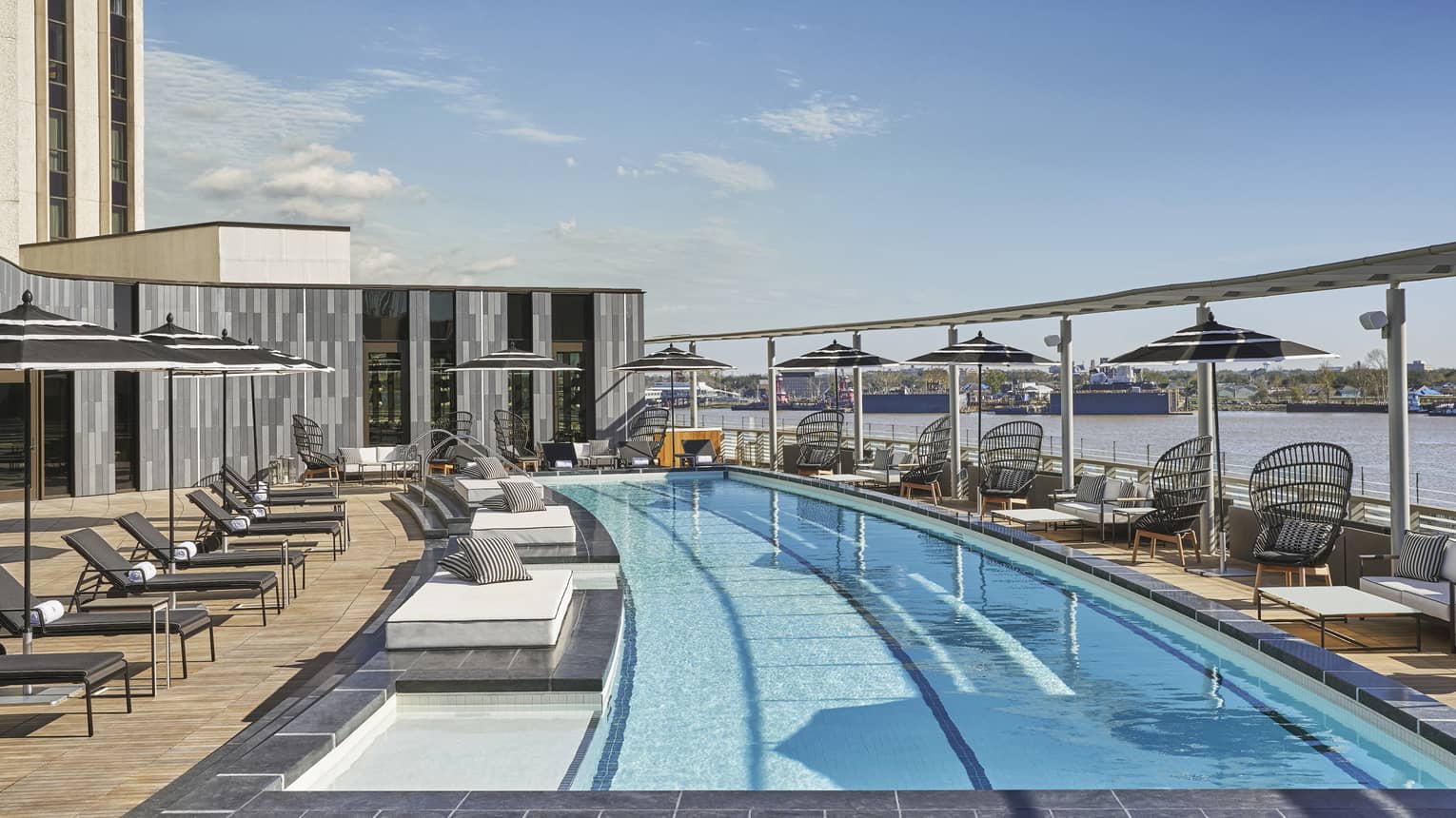 Outdoor lap pool with line of chaise lounges and egg-shaped chairs