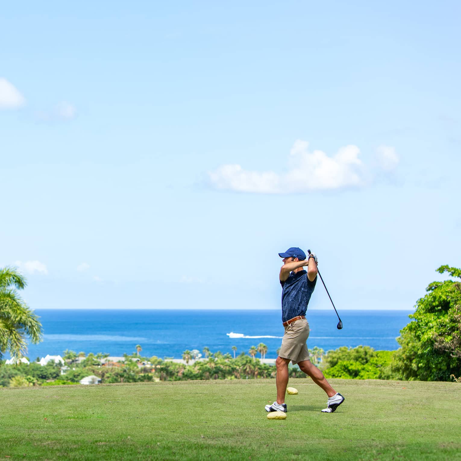 A man golfing near an ocean.