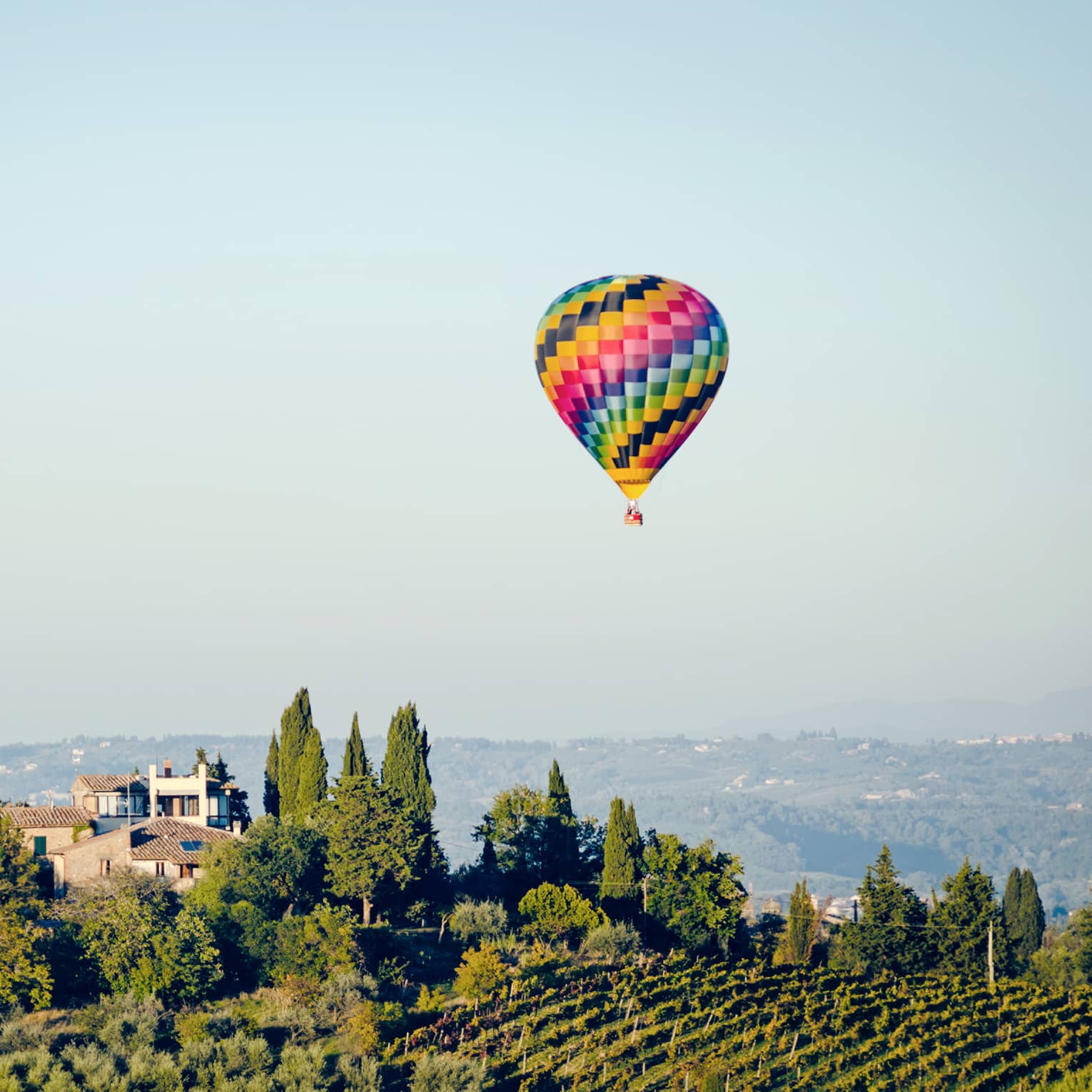 A colorful hot air balloon hovering over a vineyard in Florence