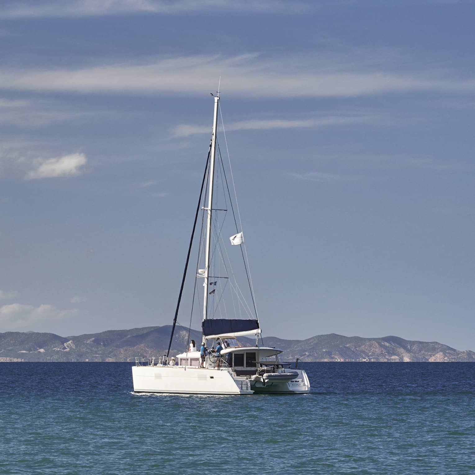 A boat sailing on the ocean with mountains in the distance.