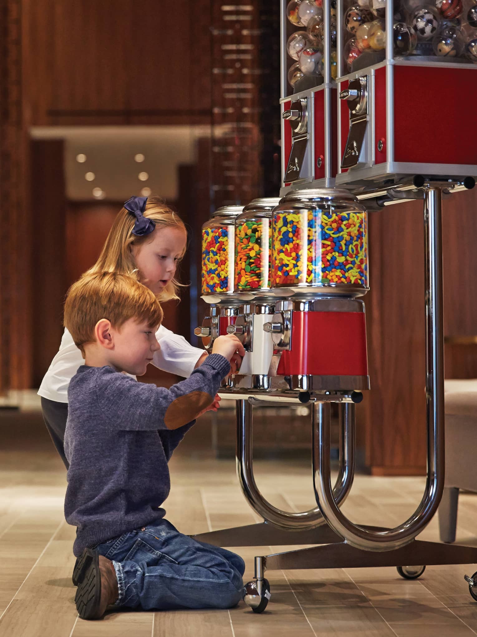 a little boy and little girl play with a gumball machine in the four seasons toronto lobby