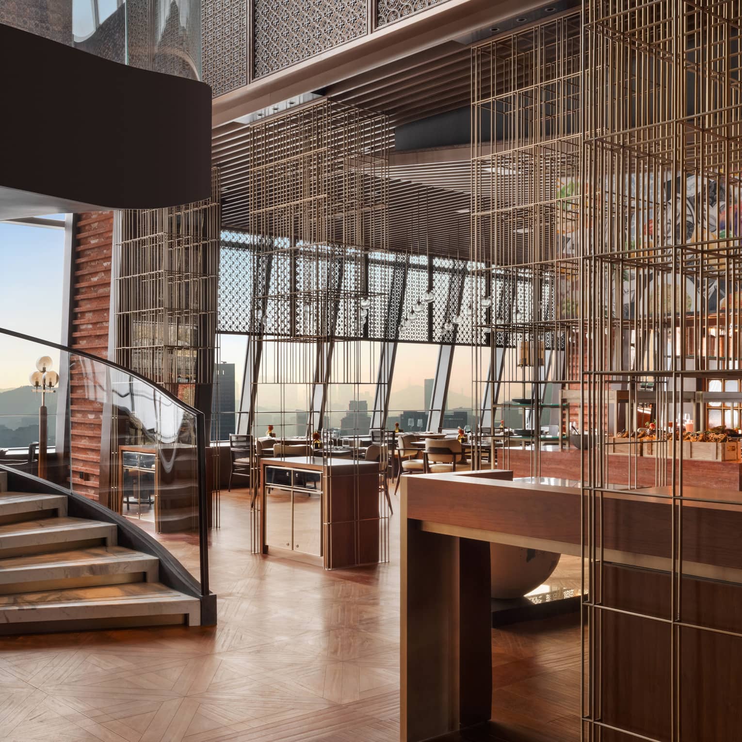 Two large, rounded sculptures set next to a curved staircase in a bright wood-hued restaurant with a wall of large windows.