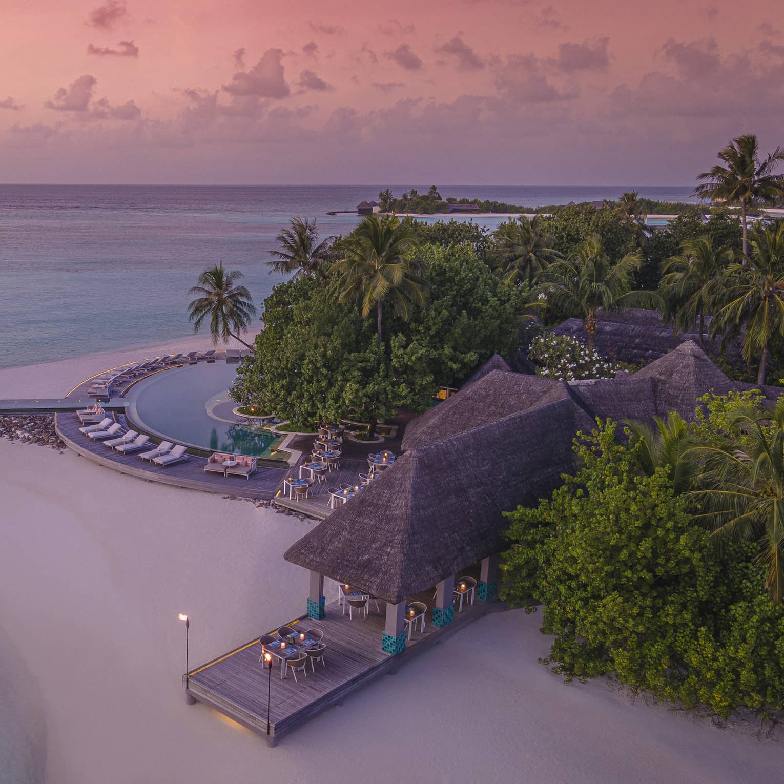Aerial view of beachfront straw roof pavilion at sunset