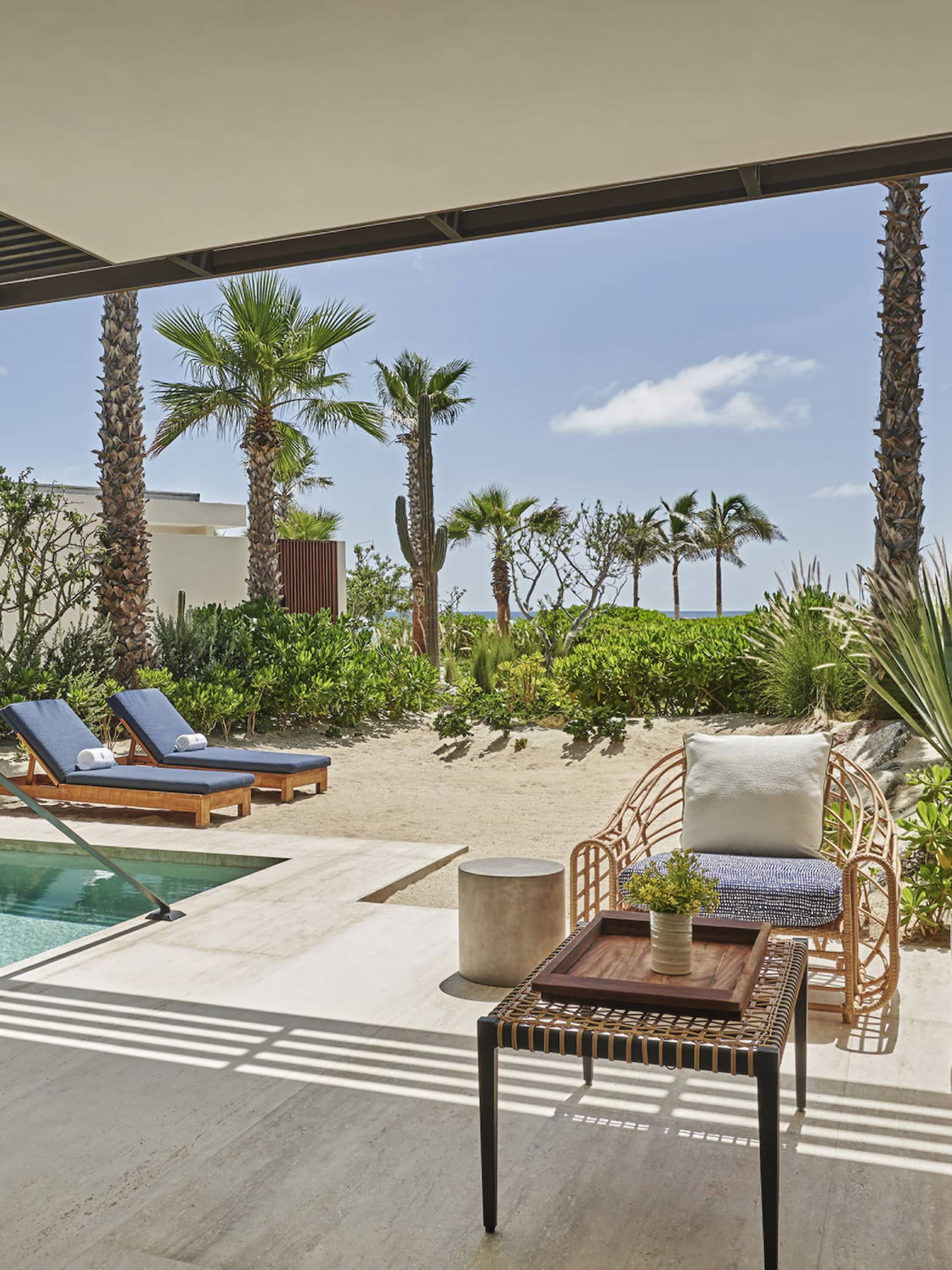 An outdoor area with sofa, chair, lounge chairs and plunge pool.