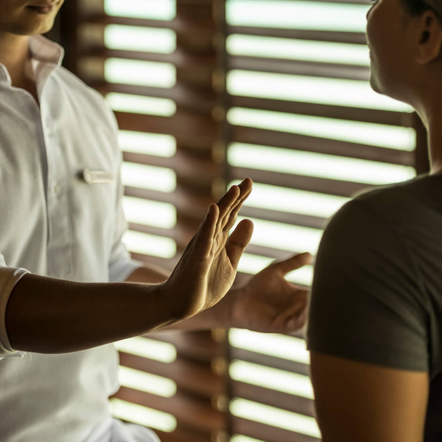 Reiki healer with eyes closed holds hand over woman's body