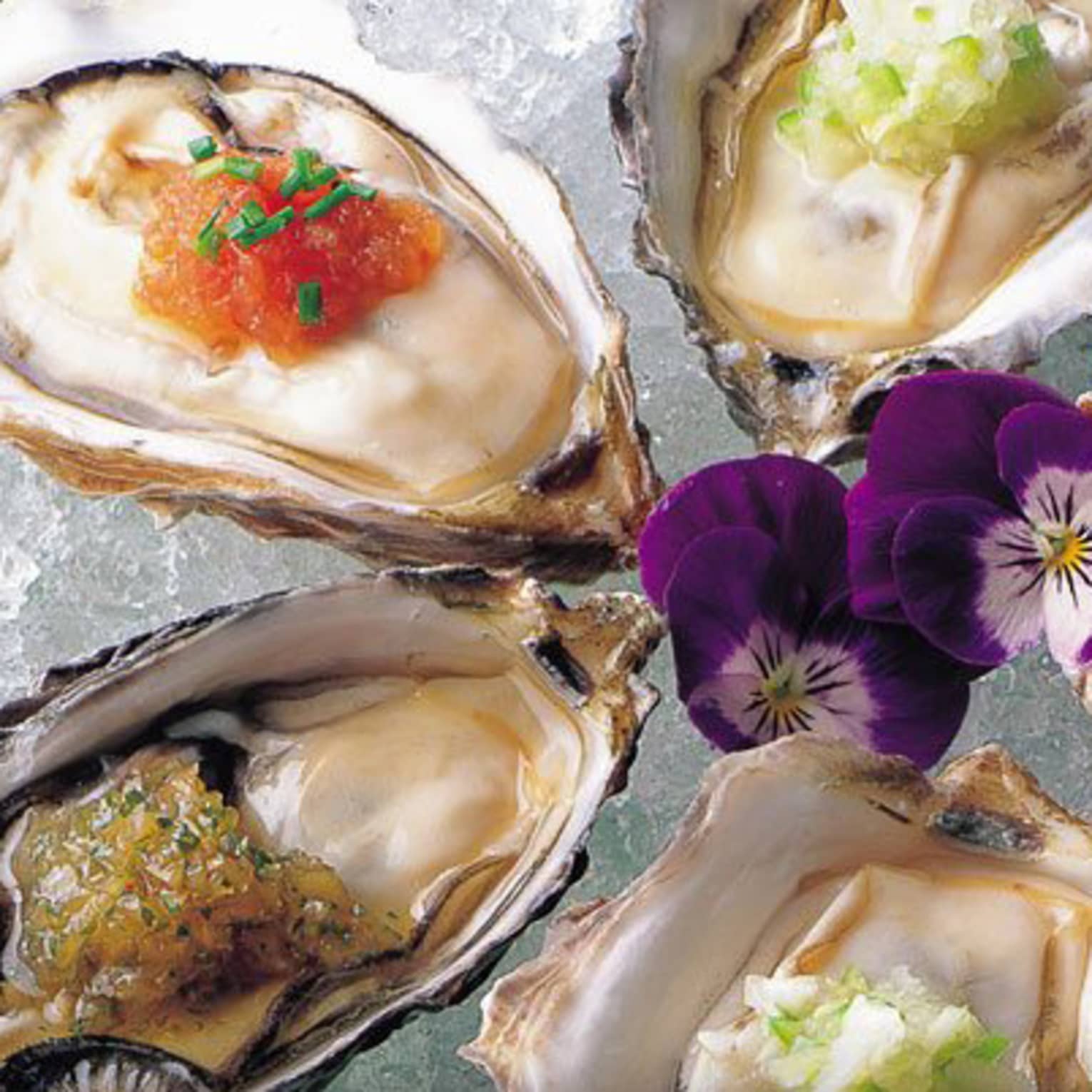 Raw oysters with Nobu Sauces and purple flowers on ice platter