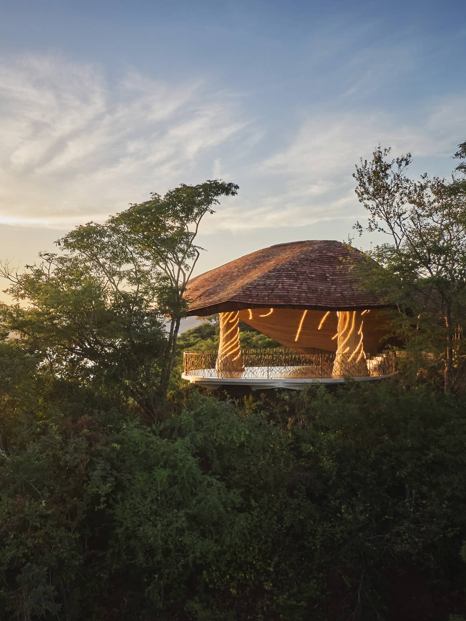 Exterior view of a covered wellness shala set on a hillside overlooking the ocean