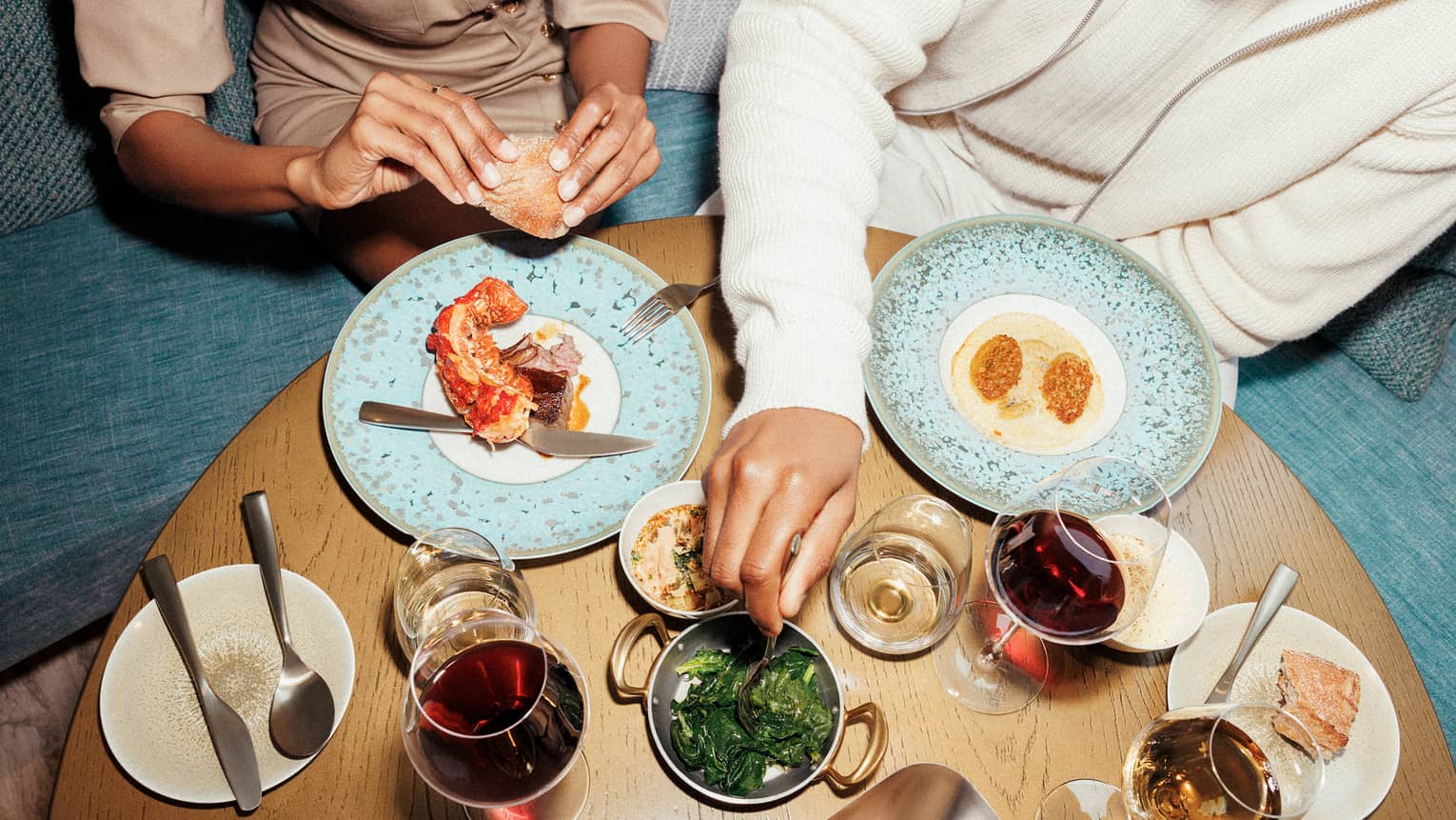 Two people sitting at a table with various food and drinks.