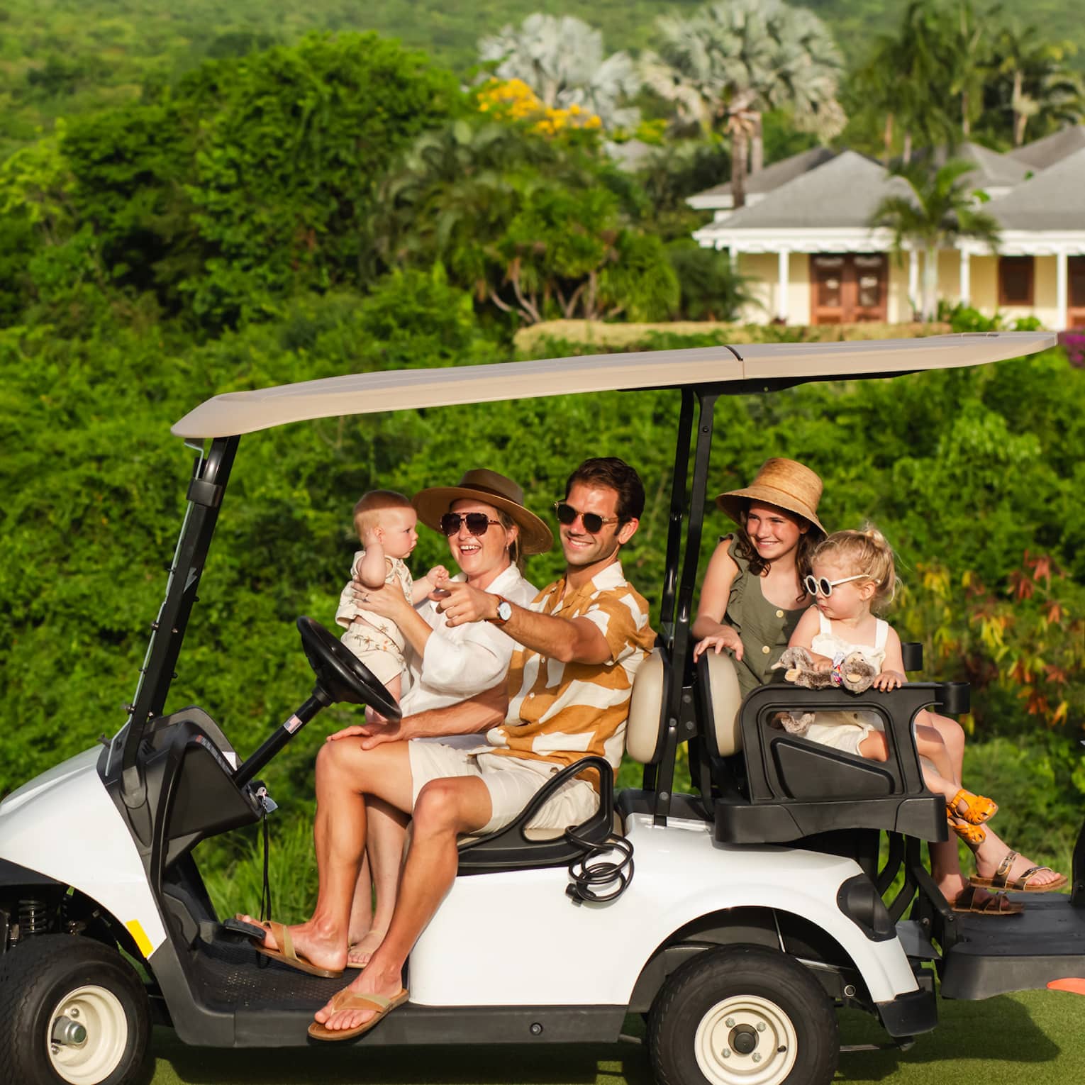 Five guests riding on a golf cart along a golf course