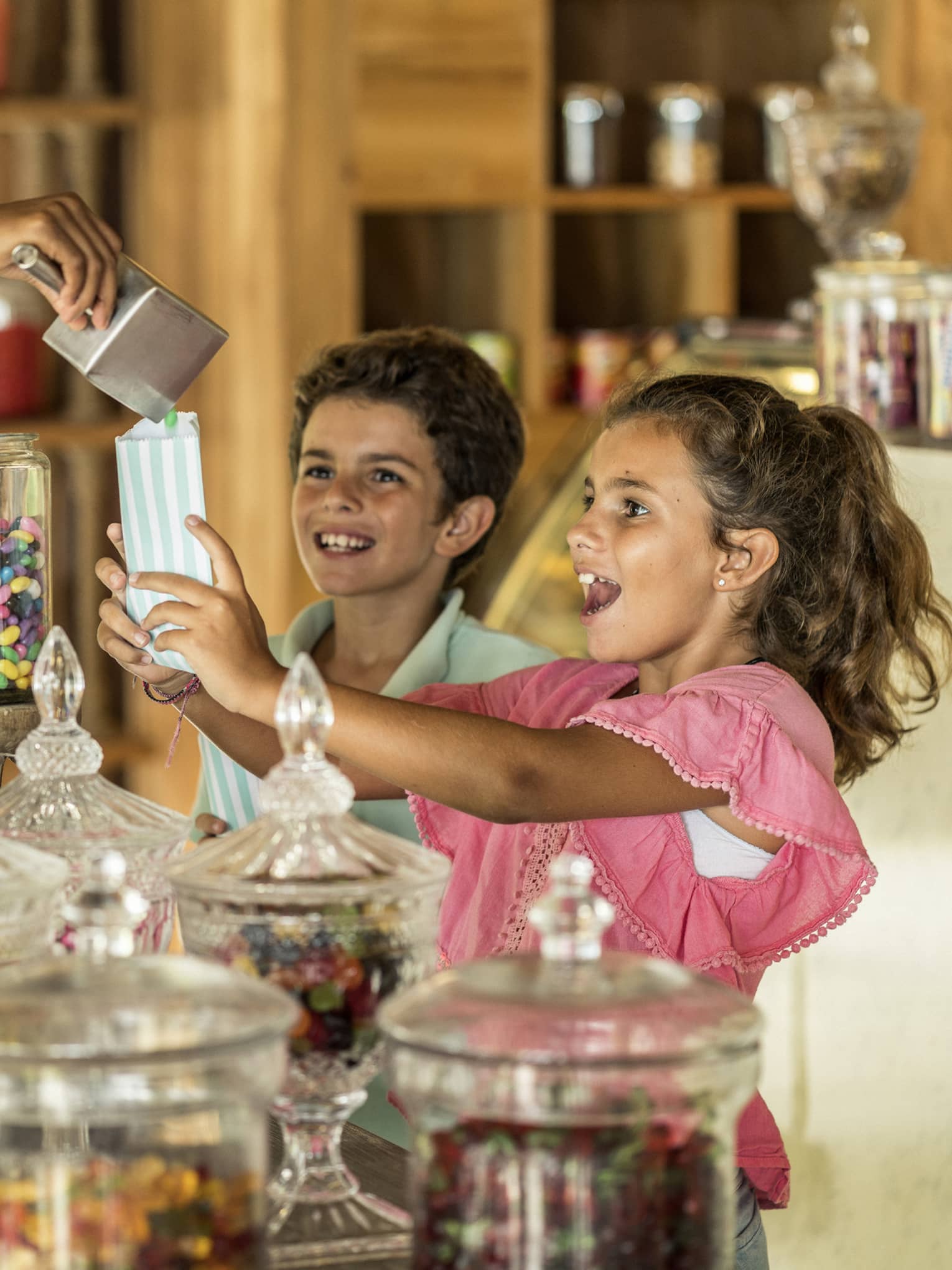 One person standing behind the candy counter, pouring candy into children's candy bags.
