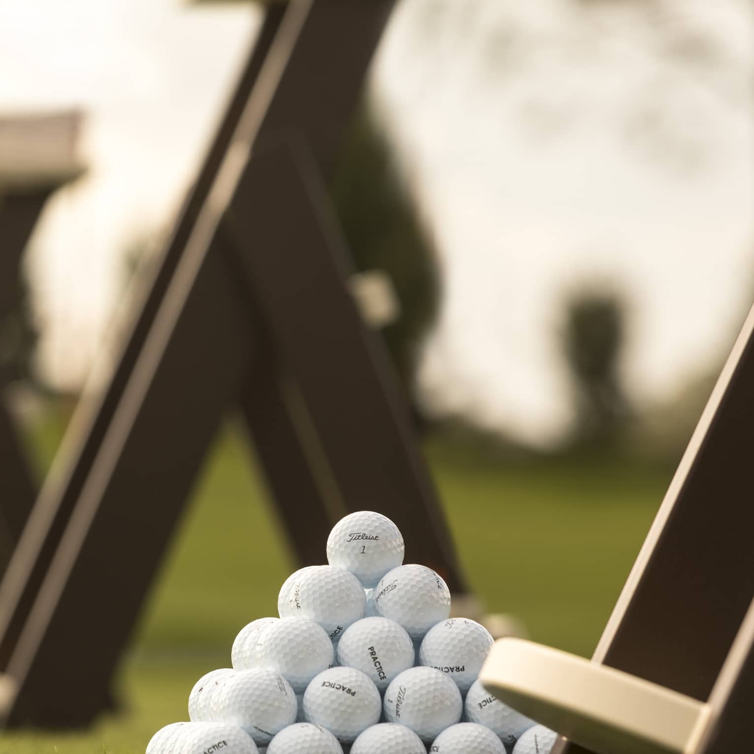 Stacks of white golf balls on lawn in front of wood panels