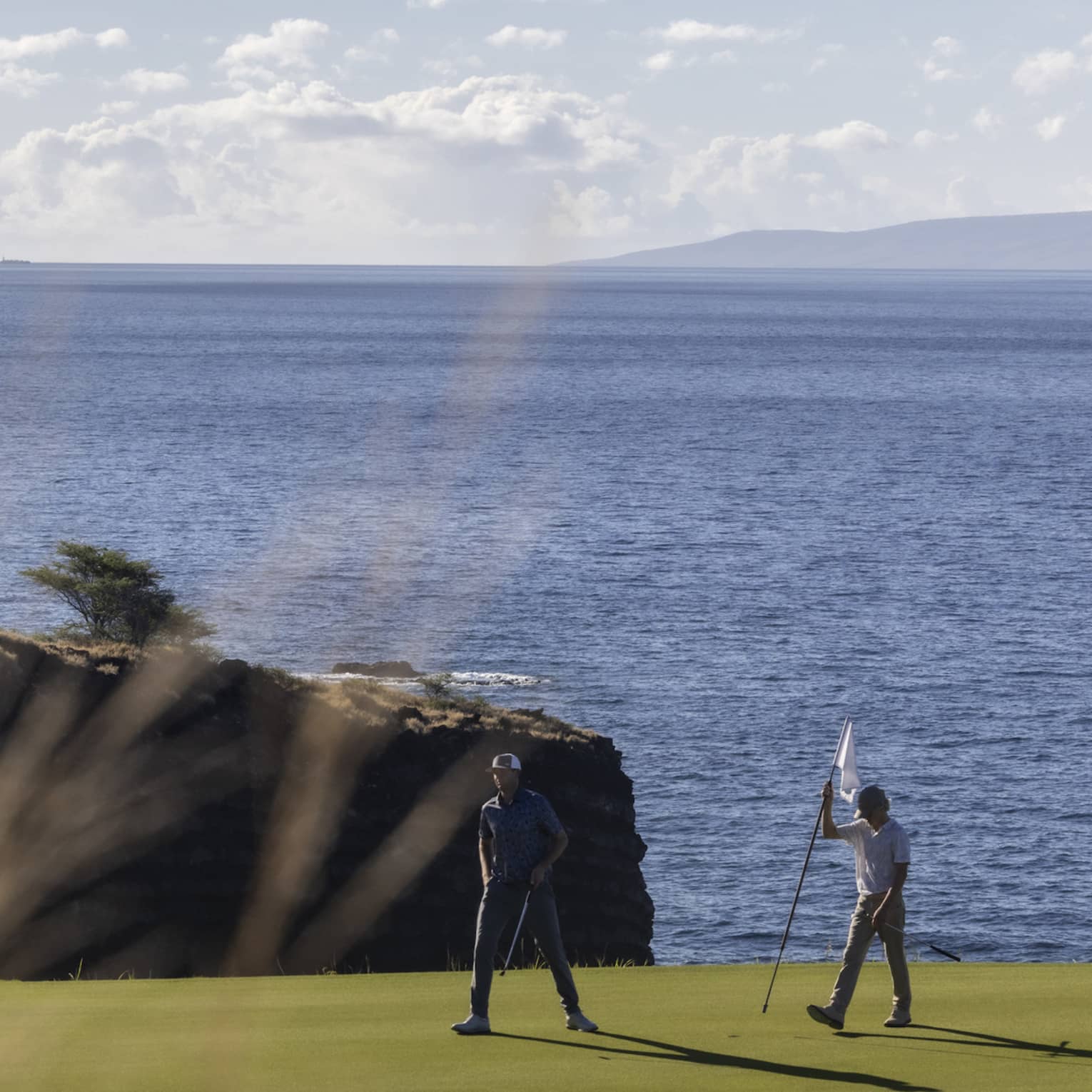 Two golfers on oceanside green at Four Seasons Resort Lanai